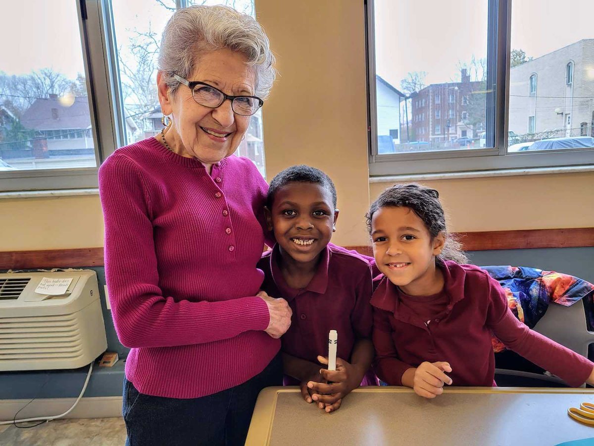 Two students smile with an older woman 